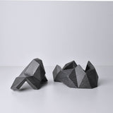 A black/dark gray, abstract geometric desk object/organize with a space-theme, resembling space rocks on the surface of a moon or planet. An interesting space-themed gift!