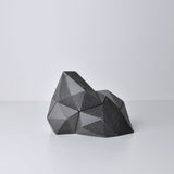 A black/dark gray, abstract geometric desk object/organize with a space-theme, resembling space rocks on the surface of a moon or planet. An interesting space-themed gift!