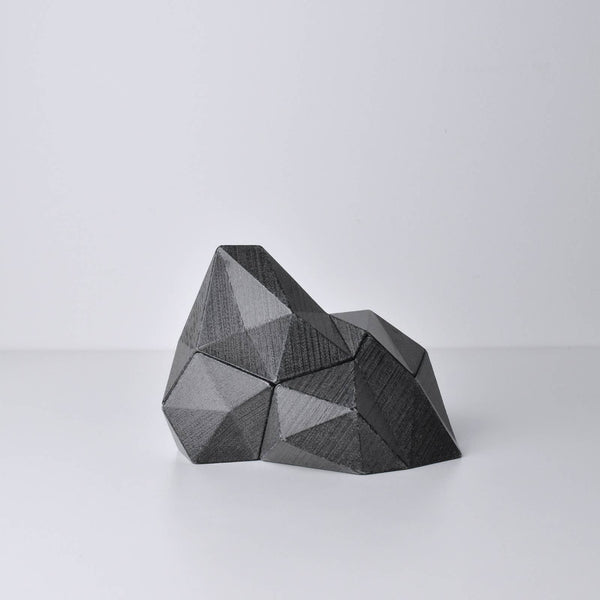 A black/dark gray, abstract geometric desk object/organize with a space-theme, resembling space rocks on the surface of a moon or planet. An interesting space-themed gift!