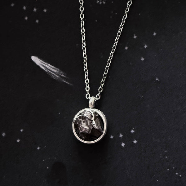 A beautiful and unique small round chunky raw meteorite necklace in a silver tone deep bezel. The perfect space-themed necklace jewelry gift!