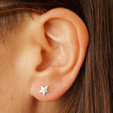 A cute mismatched pair of sterling silver moon and star stud earrings - the perfect space jewelry gift for a space lover! Showing the star earring on an ear.
