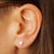 A pair of tiny sterling silver star stud earrings - the perfect space jewelry gift for a space lover! Shown on an ear.