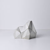 A white, abstract geometric desk object with a space-theme, resembling space rocks on the surface of a moon or planet. An interesting space-themed gift!