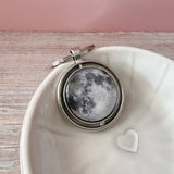 A spinning Moon fidget keychain with a full moon on one side and new moon on the other side under glass. A fun space moon keychain gift for men or women!