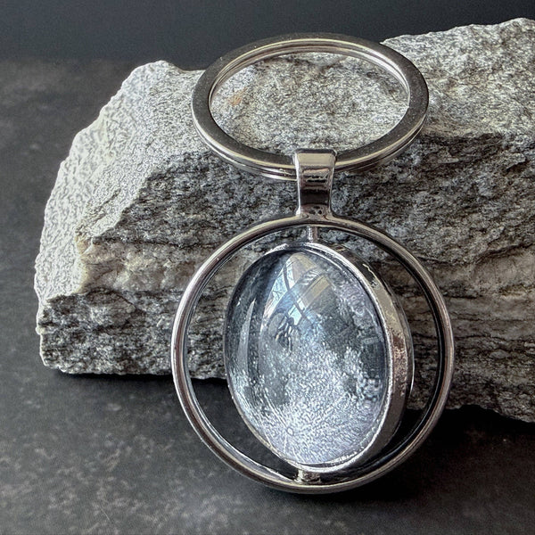 A spinning Moon fidget keychain with a full moon on one side and new moon on the other side under glass. A fun space moon keychain gift for men or women!