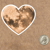 A vinyl heart moon sticker, perfect for any lover of the moon or space!