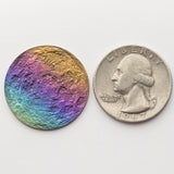 A double-sided rainbow full moon coin made from anodized niobium - a colorful and unique moon gift! Showing near side of the Moon next to a quarter.