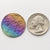 A double-sided rainbow full moon coin made from anodized niobium - a colorful and unique moon gift! Showing near side of the Moon next to a quarter.