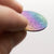 Hand holding a double-sided rainbow full moon coin made from anodized niobium - a colorful and unique moon gift! Showing far side of the Moon.