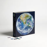 A round earth puzzle by Four Point Puzzles - the perfect space gift! Front of box with loose puzzle pieces.