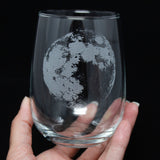 Hand holding an etched stemless wine glass with a realistic full moon, space themed