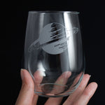 Hand holding an etched stemless wine glass with the planet Saturn, space themed