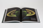 A book of cool photos of space from NASA, open to a real photo of Saturn.