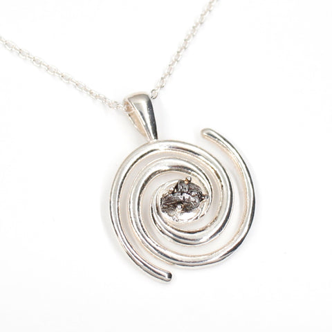 Spiral galaxy necklace with a genuine Campo del Celio meteorite in the center! A solid sterling silver spiral galaxy necklace is the perfect space gift. Shown on white background.